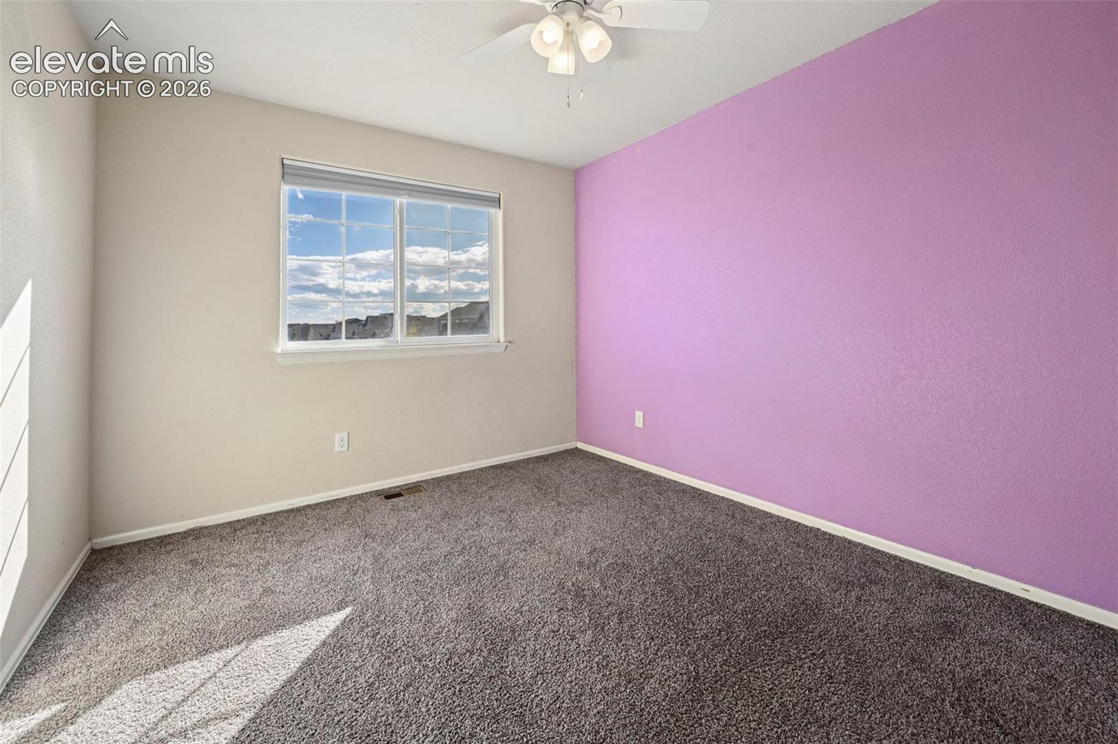 Room featuring neutral carpeting, a multi-pane window, and a ceiling fan with integrated lighting