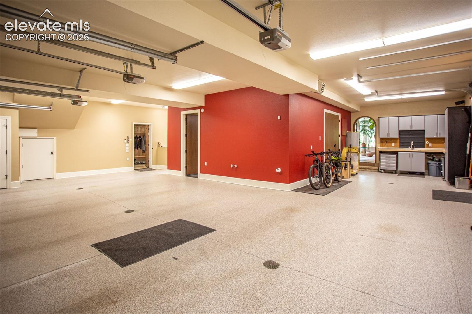Spacious 4 car garage with durable epoxy floor, built-in cabinetry with a sink.