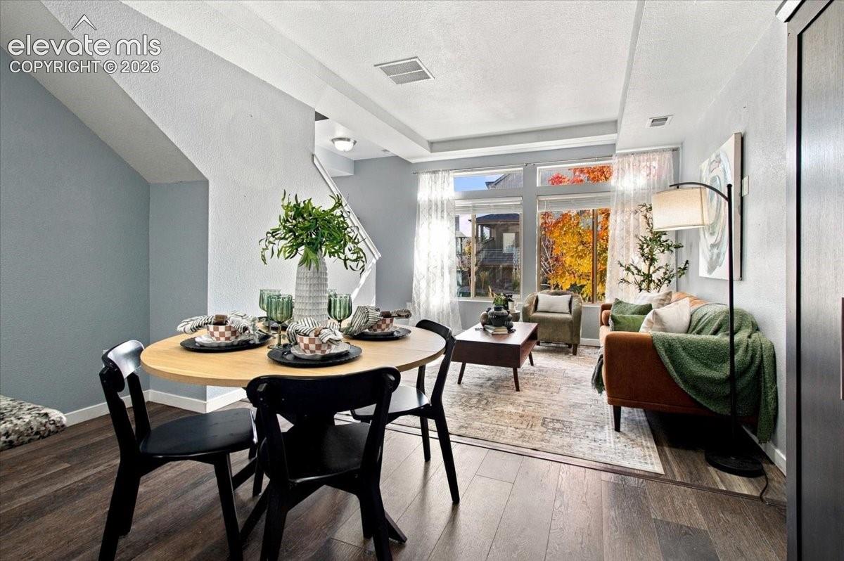 Open-concept living space with wood-finish flooring, a contemporary dining area, and large windows providing abundant natural light