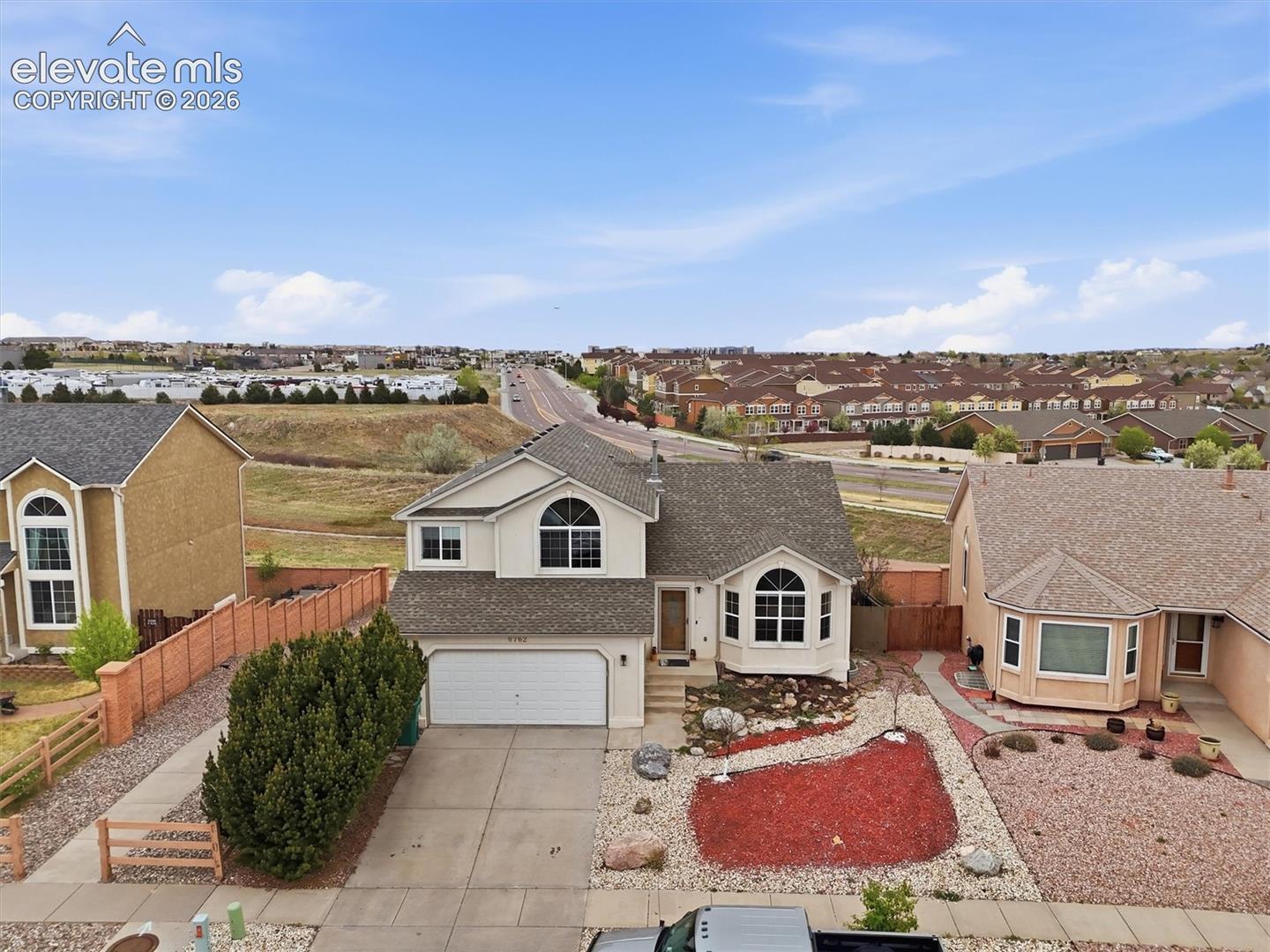 Two-story residence with an attached two-car garage, bay windows, and a landscaped front yard with decorative rock and mulch