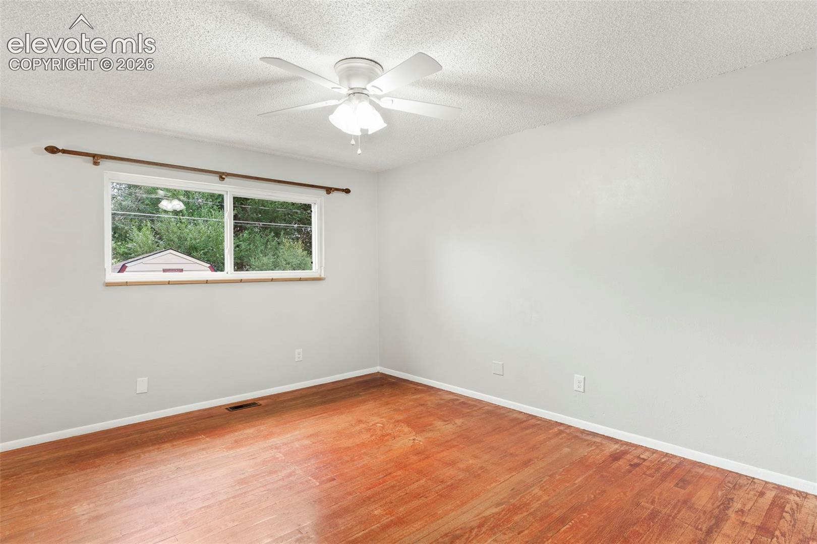 Wood-finish flooring with light-toned walls and a white ceiling fan with light fixture