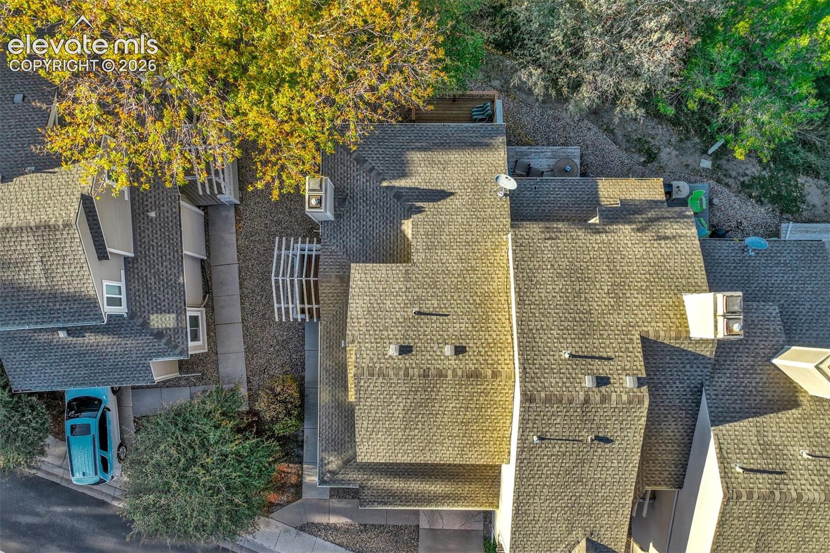 Aerial view of shingle roofing, multi-level exterior structure, structural chimneys, and mature trees
