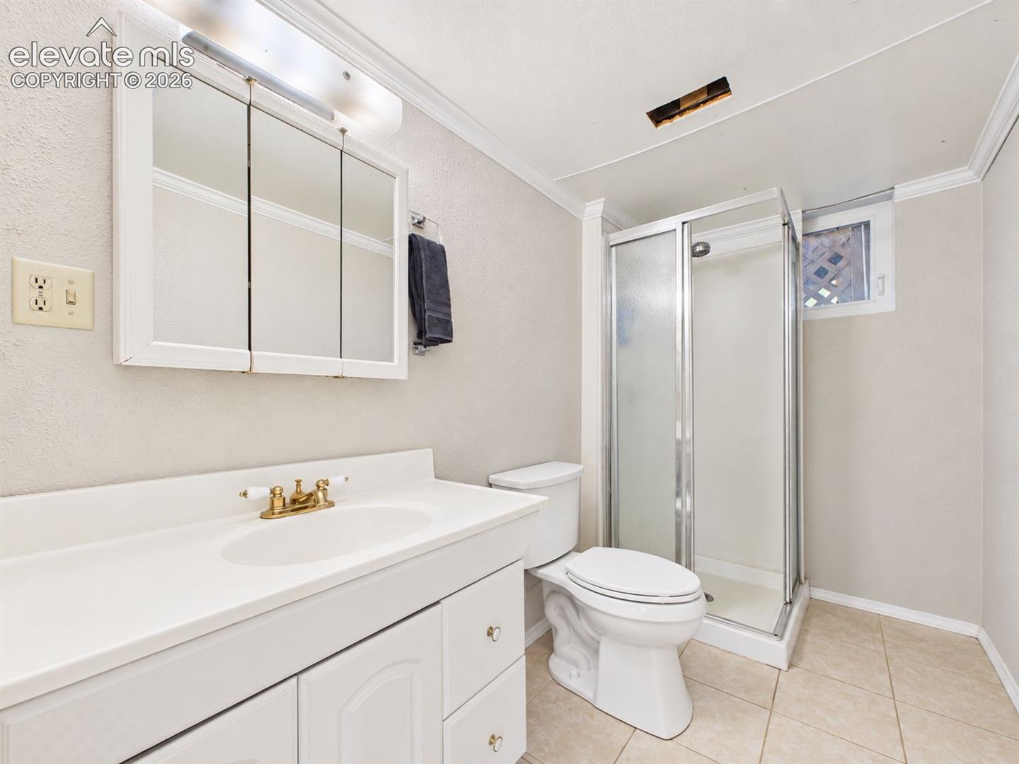3/4 bathroom features a walk-in shower with glass enclosure, white vanity, mirrored medicine cabinet, tile flooring, and a small window for natural light.