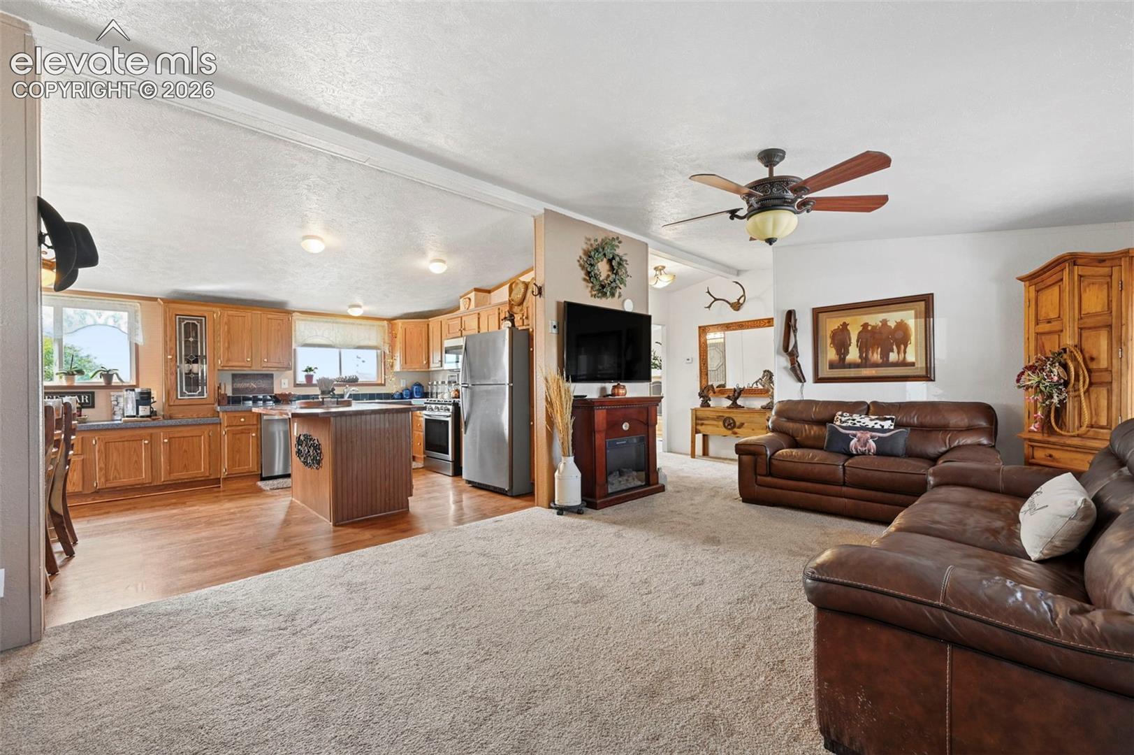 Kitchen featuring wood cabinetry, a center island with beadboard detailing, and stainless steel appliances