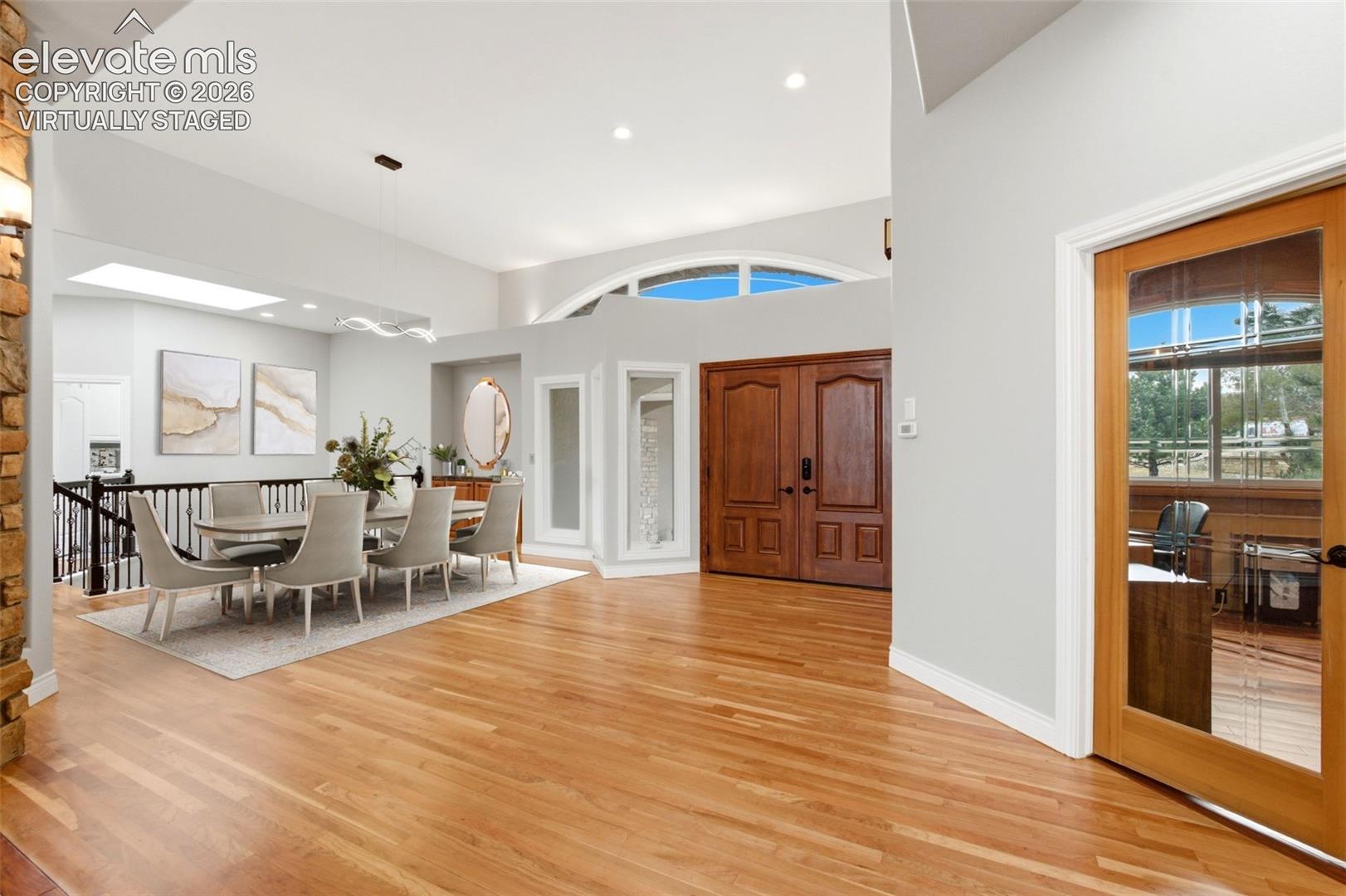 Virtually staged. Hardwood flooring, double entry doors, vaulted ceilings, arched transom windows, and an open-concept dining area with a skylight
