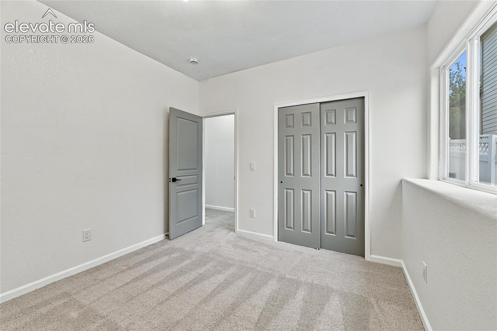 Neutral-toned bedroom featuring wall-to-wall carpeting, grey-finished paneled interior doors, and a double-door reach-in closet