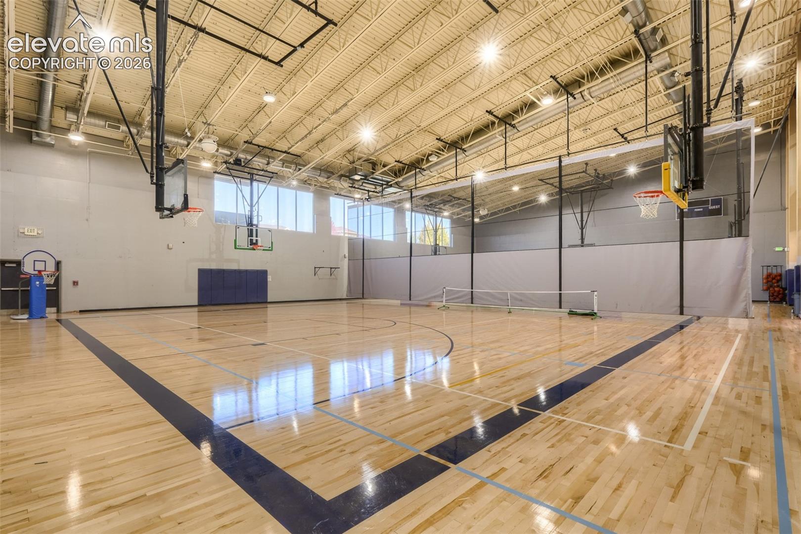 Full-size gymnasium featuring a hardwood court, multiple basketball hoops, high ceilings.