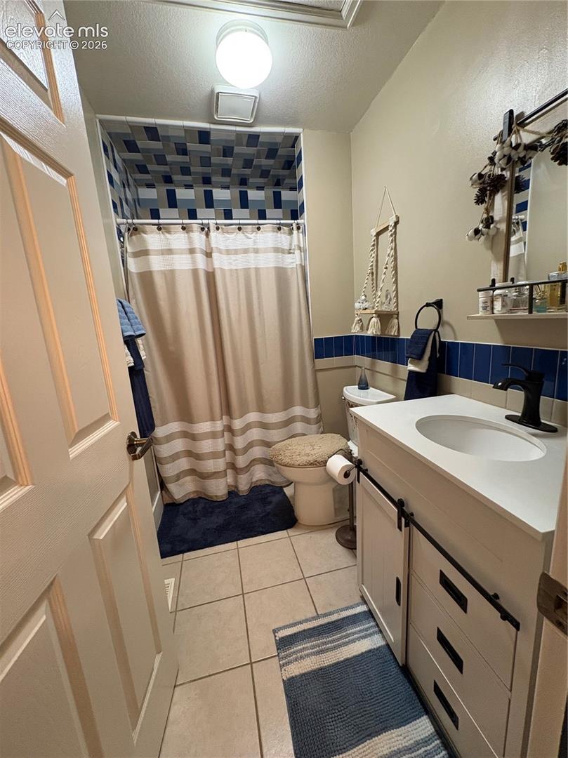 White vanity with a single basin sink, matte black faucet, and barn-door style cabinet fronts