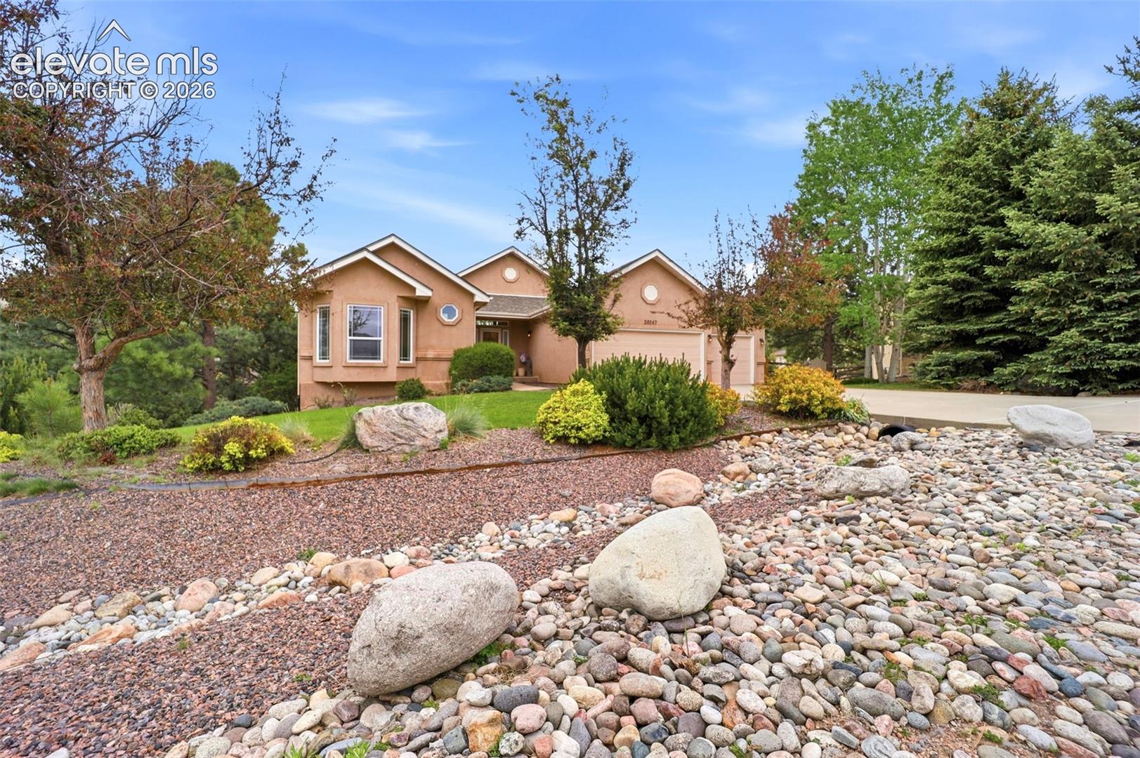Experience elevated Colorado living in this exceptional ranch-style home nestled atop scenic Monument Hill. Surrounded by towering pines, dramatic rock formations, and expansive mountain views, this property offers the perfect combination of privacy, comfort, and accessibility— all just minutes from I-25 with convenient access to Colorado Springs, Denver, and DIA. Designed for effortless one-level living, the main level welcomes you with soaring vaulted ceilings, abundant natural light, and a spacious open layout that perfectly captures the beauty of the surrounding landscape. Large windows frame the incredible scenery, creating a warm and inviting atmosphere throughout the home. At the center of it all is a beautifully appointed kitchen built for both everyday living and memorable gatherings. Featuring quartz countertops, upgraded 42” cabinets, a stainless steel farmhouse sink, gas cooktop, and double ovens, this space blends style and functionality while offering plenty of room to cook, entertain, and connect. With 5 generously sized bedrooms, there is ample space for guests, home offices, hobbies, or growing households. The finished walk-out basement with impressive 9-foot ceilings expands the living space even further, offering endless possibilities for recreation, entertaining, or multi-generational living.The setting feels peaceful and secluded, yet remains close to everything you need— from shopping and dining to hiking trails, outdoor adventures, and everyday conveniences. Whether you are enjoying crisp mountain mornings, relaxing evenings under the trees, or taking in the ever-changing Colorado skies, this home delivers a lifestyle that feels both refined and refreshing. Additional recent improvements add comfort and peace of mind, including a new furnace and air conditioner (2025), water softener (2025), radon mitigation system (2025), living room ceiling fan (2025), and reverse-osmosis water filtration system in the kitchen (2026).