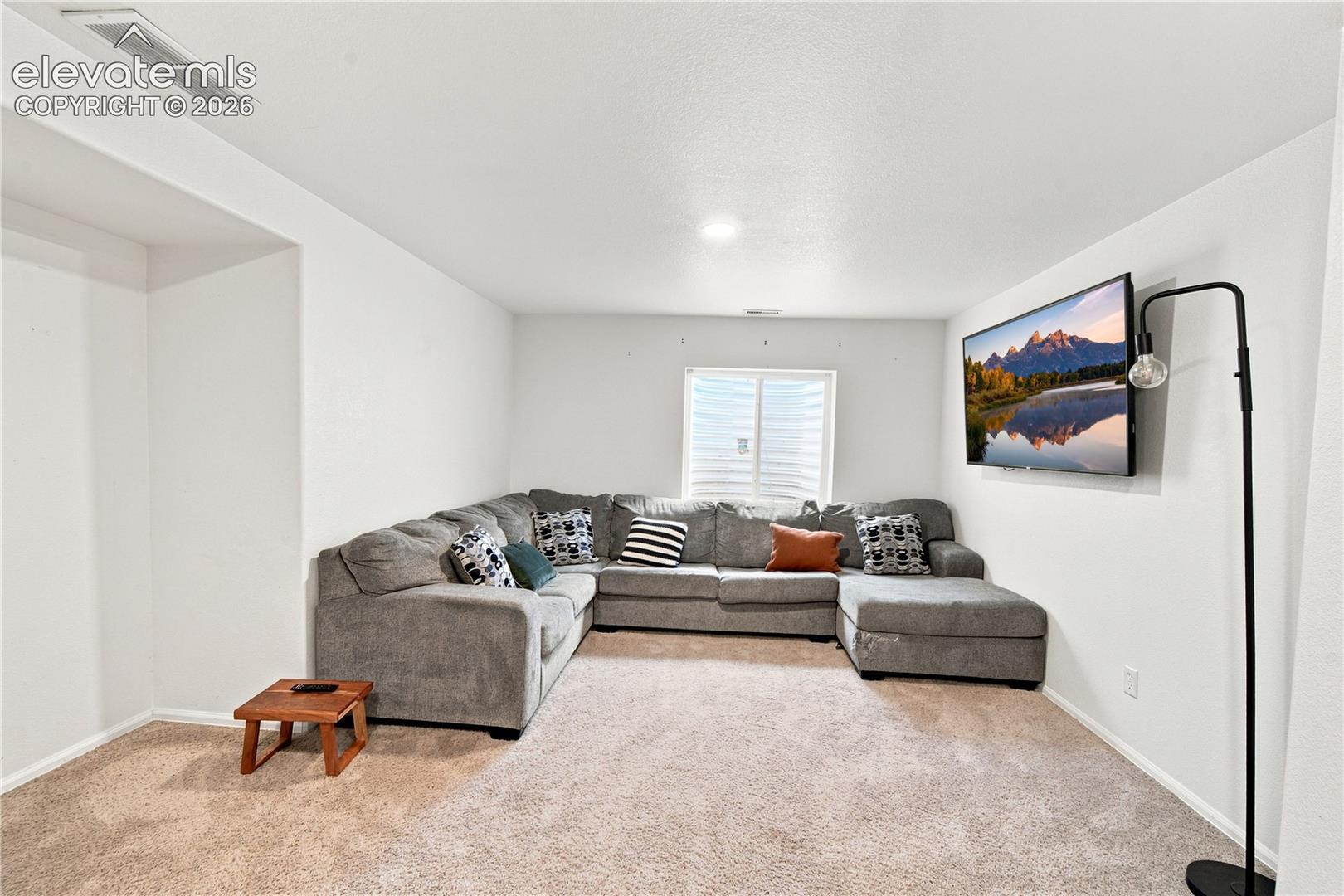 Recessed lighting, wall-mounted television, and neutral tone carpeting