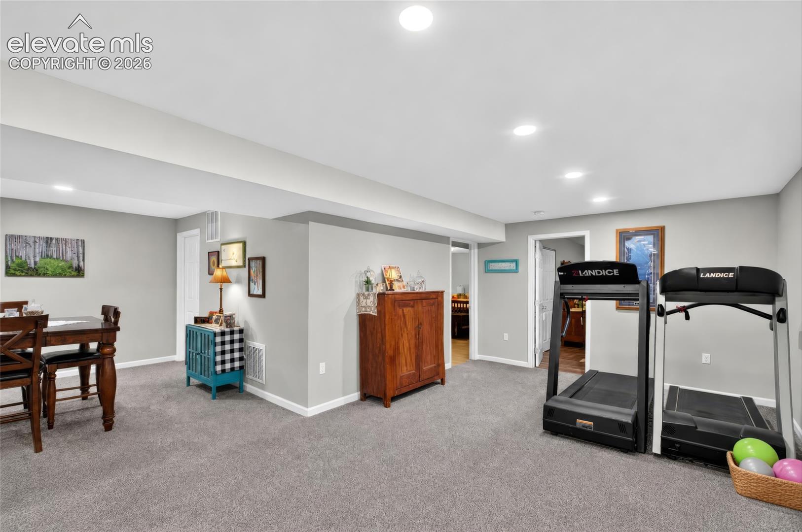 Recessed ceiling lighting, light gray wall paint, and gray carpet flooring