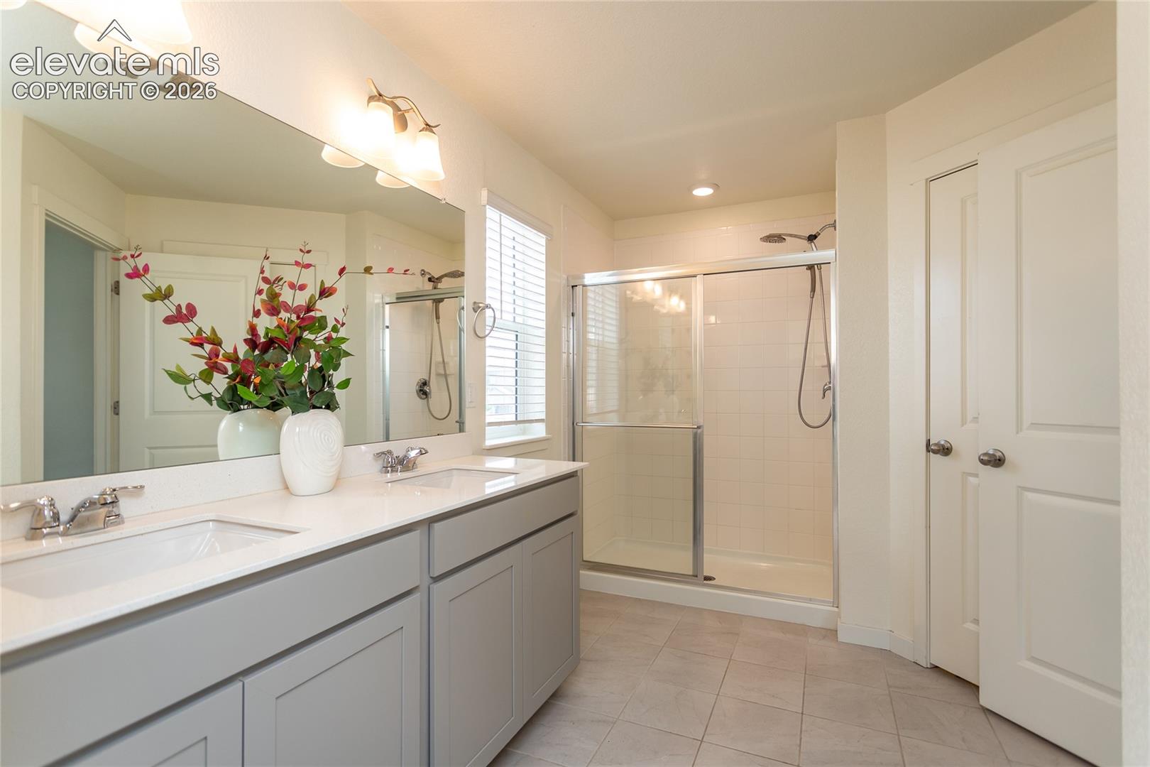 Beautiful primary bathroom has tile flooring and quartz contertops.