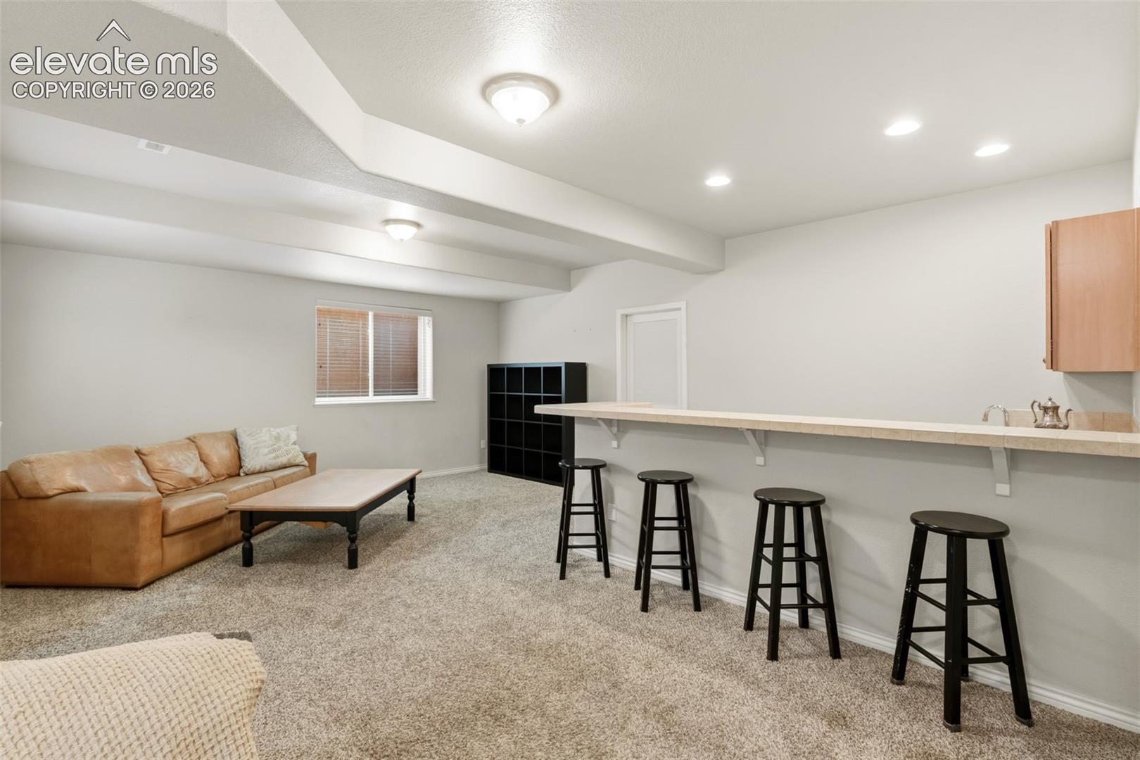 Spacious recreational area featuring recessed lighting, a built-in bar, and neutral-toned carpeting