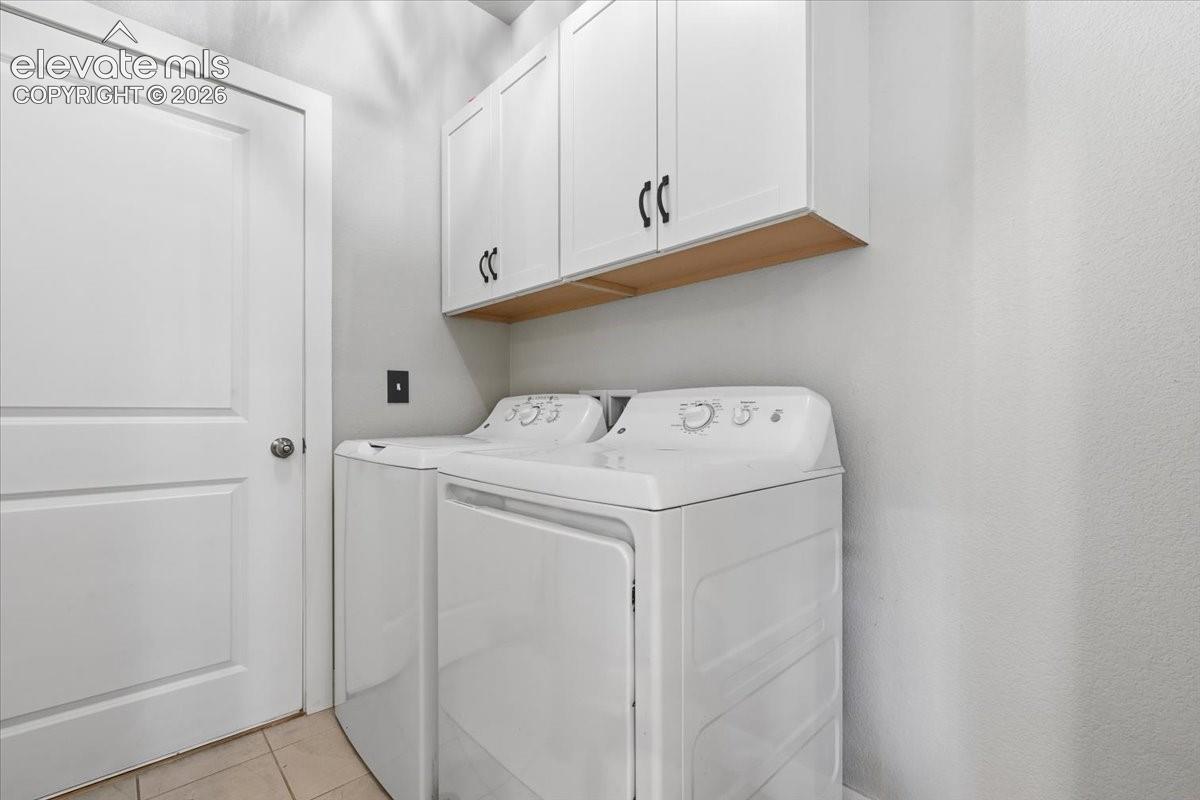 White upper cabinetry with black hardware, wood-finish shelving, and tiled flooring