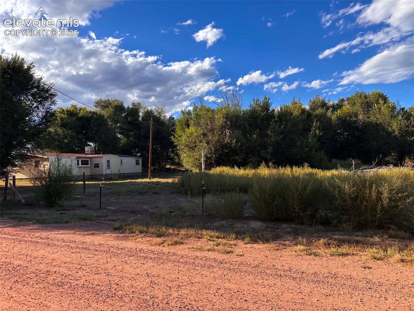 Expansive rural lot featuring mature trees, native vegetation, and a single-story dwelling situated on a natural landscape