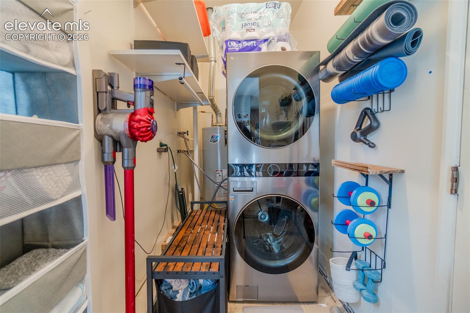 Stacked stainless steel washer and dryer unit, built-in open shelving, and integrated water heater