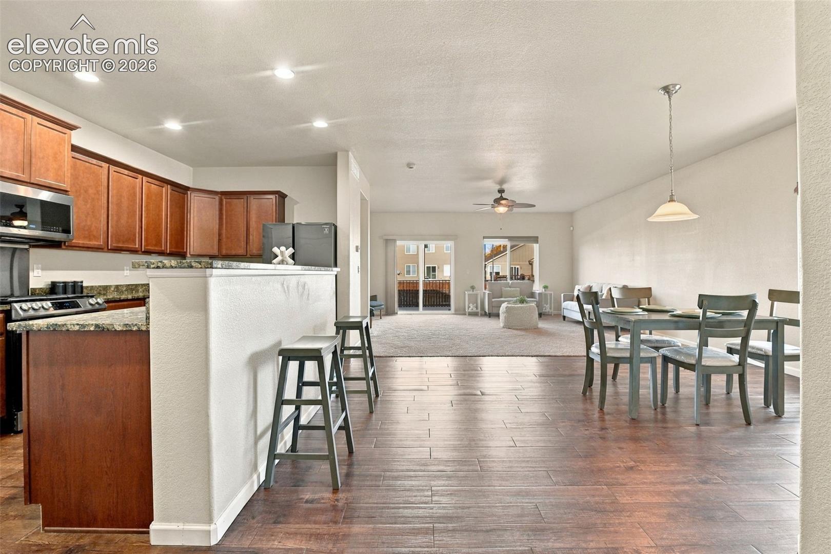 Kitchen featuring stained wood cabinetry, stone-surface countertops, and recessed lighting, paired with wood-finish tile flooring and a ceiling fan