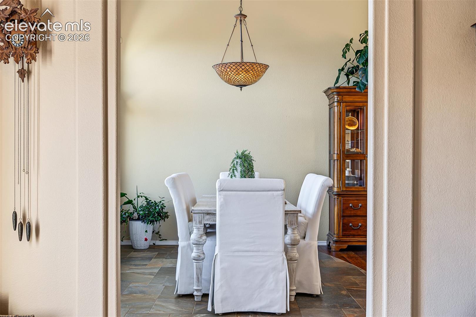 View from the kitchen into the dining area, highlighting the decorative chandelier, tile flooring, and architectural archway.