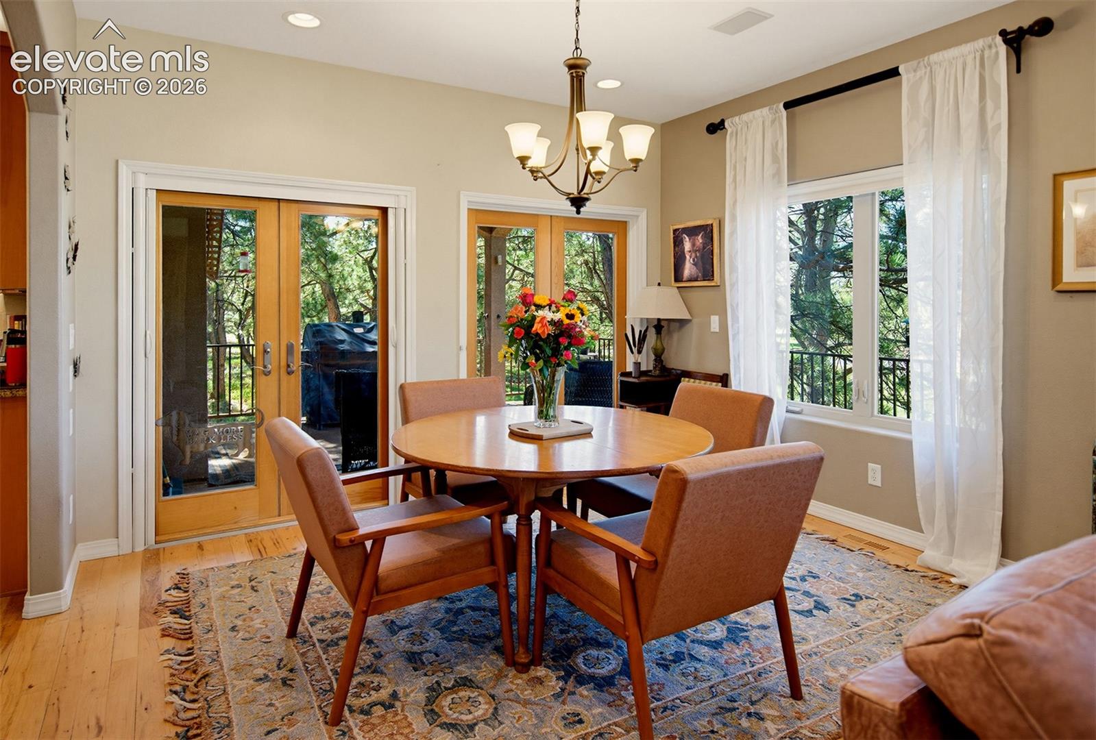 Recessed lights, beautiful wood flooring, dbl French doors, a lg window &  chandelier create such a warm, inviting space to share a meal