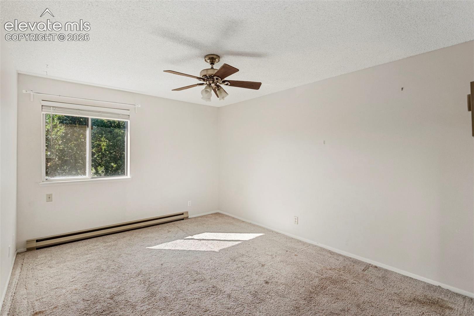 Ceiling fan with light fixture, wall-to-wall carpeting, and baseboard heating unit