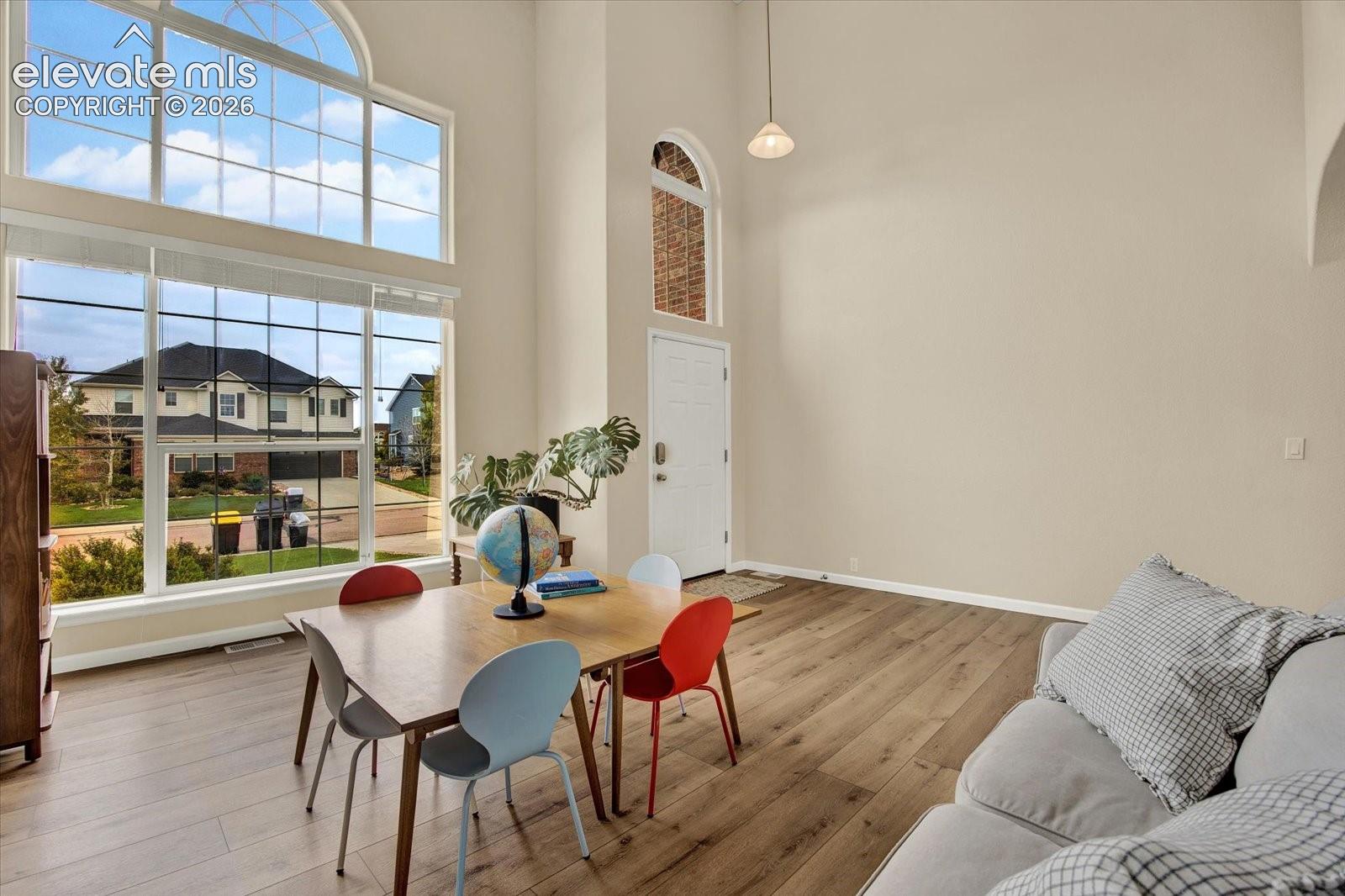 Double-height ceilings with expansive multi-pane windows, arched transom detailing, wood-finish flooring, and recessed pendant lighting
