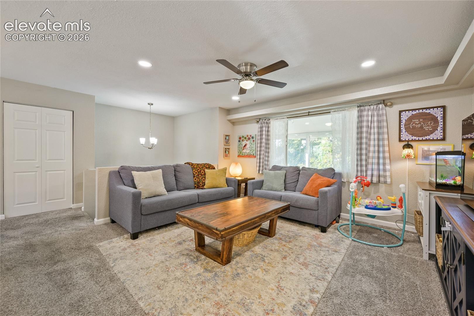 Living space featuring a coffered ceiling, recessed lighting, ceiling fan, and carpeted flooring