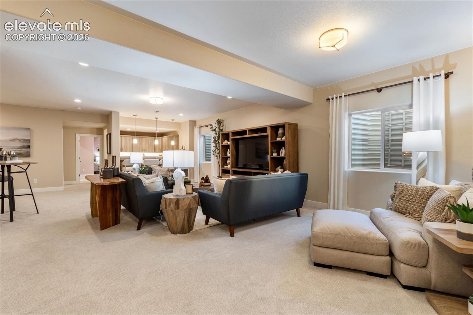 Open-concept living space featuring high ceilings, a built-in wood media console, recessed lighting, carpeted flooring, and a window with a window well