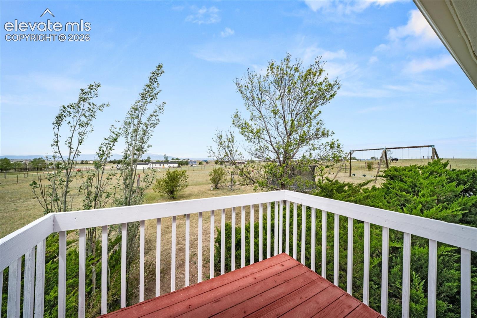 Exterior wood deck featuring a red-stained surface and white painted railings