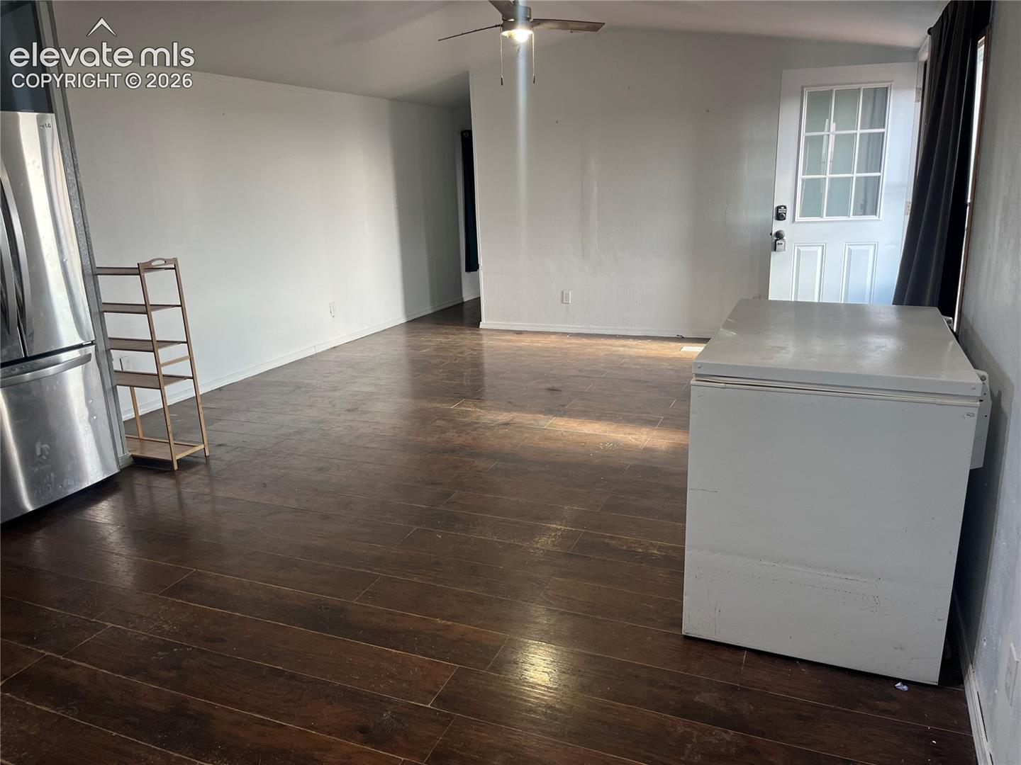 Wood-finish flooring with white walls and a ceiling fan