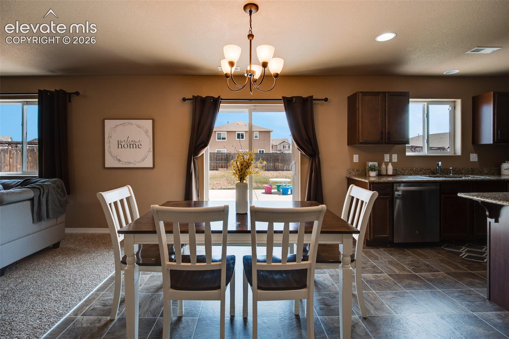 Dining Area off the Kitchen with tile floor, a modern light fixture, and slider to the backyard patio.