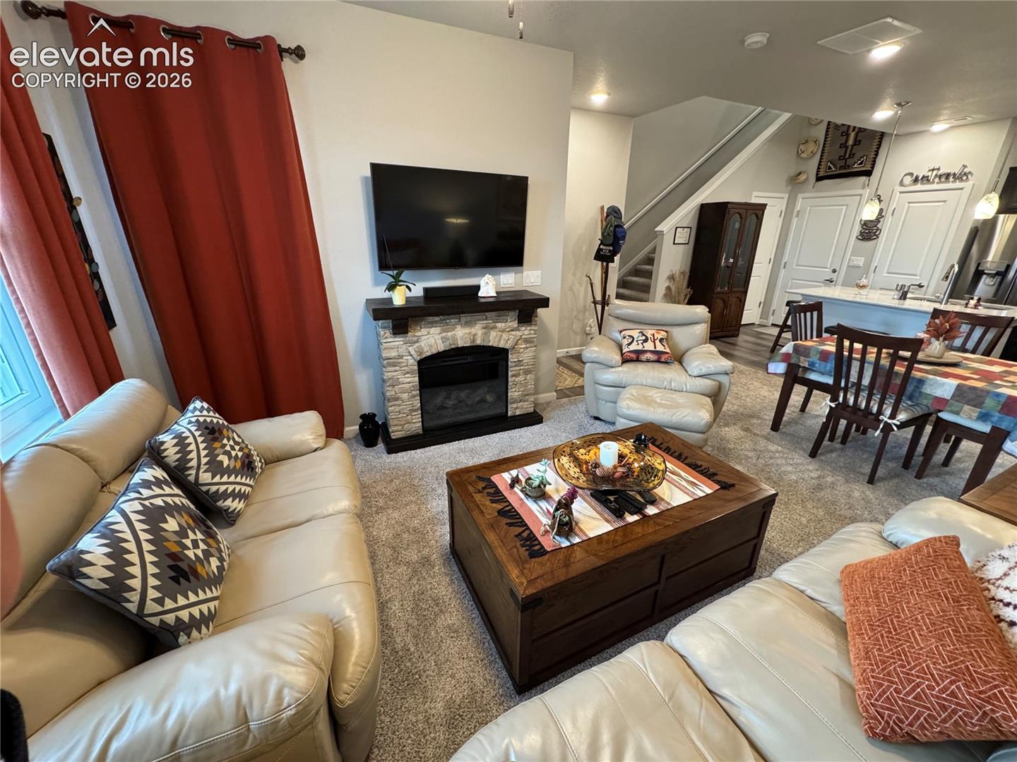 Fireplace featuring a stone-style facade and a dark wood mantel, neutral wall-to-wall carpeting, and recessed lighting