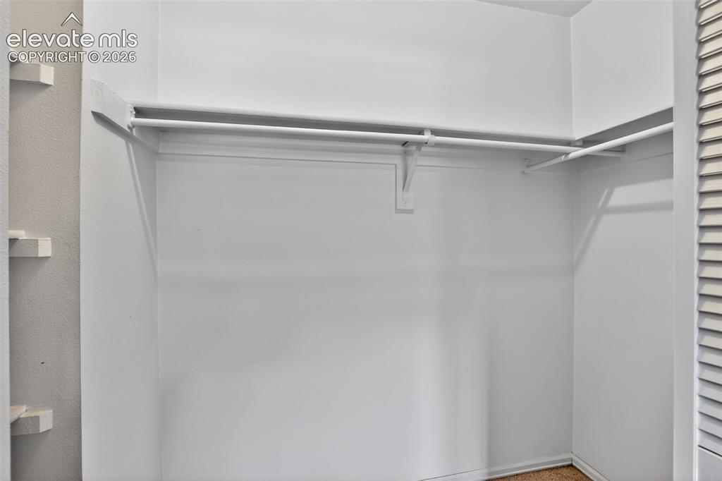 White-painted closet with integrated shelving and hanging rods