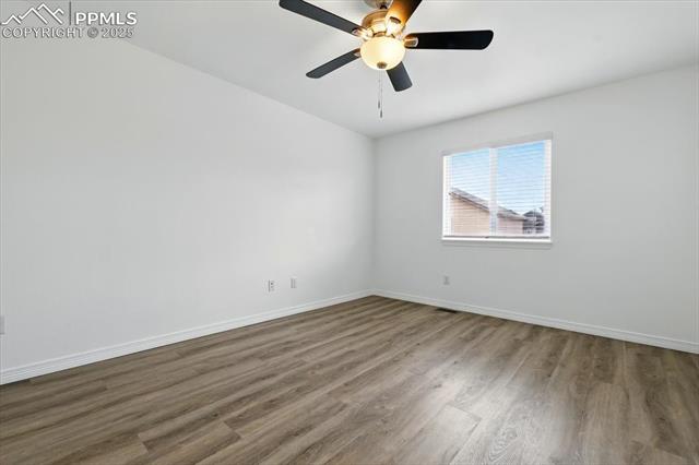 Empty room featuring wood finished floors, baseboards, and a ceiling fan