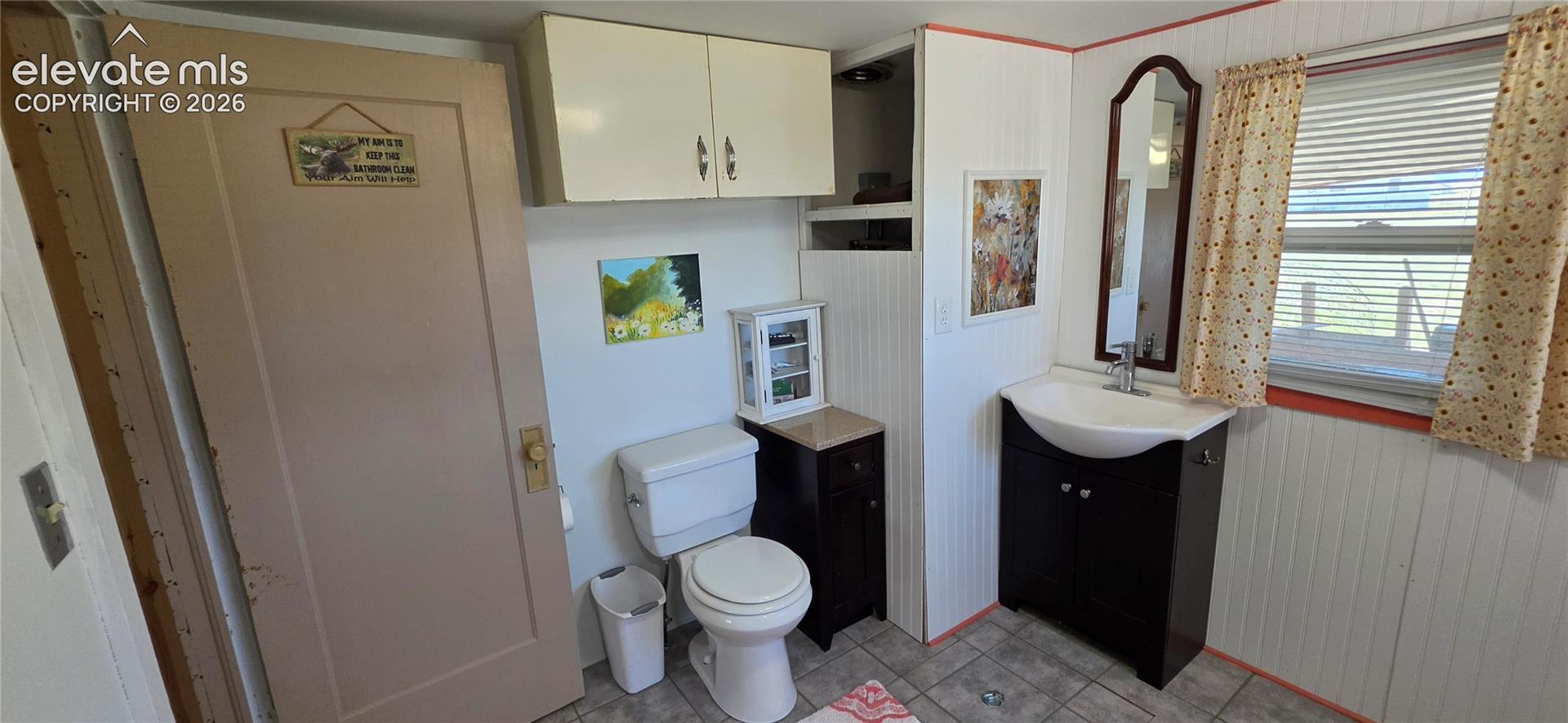 White beadboard walls, dark wood-finish vanity with an integrated basin sink, and a framed mirror