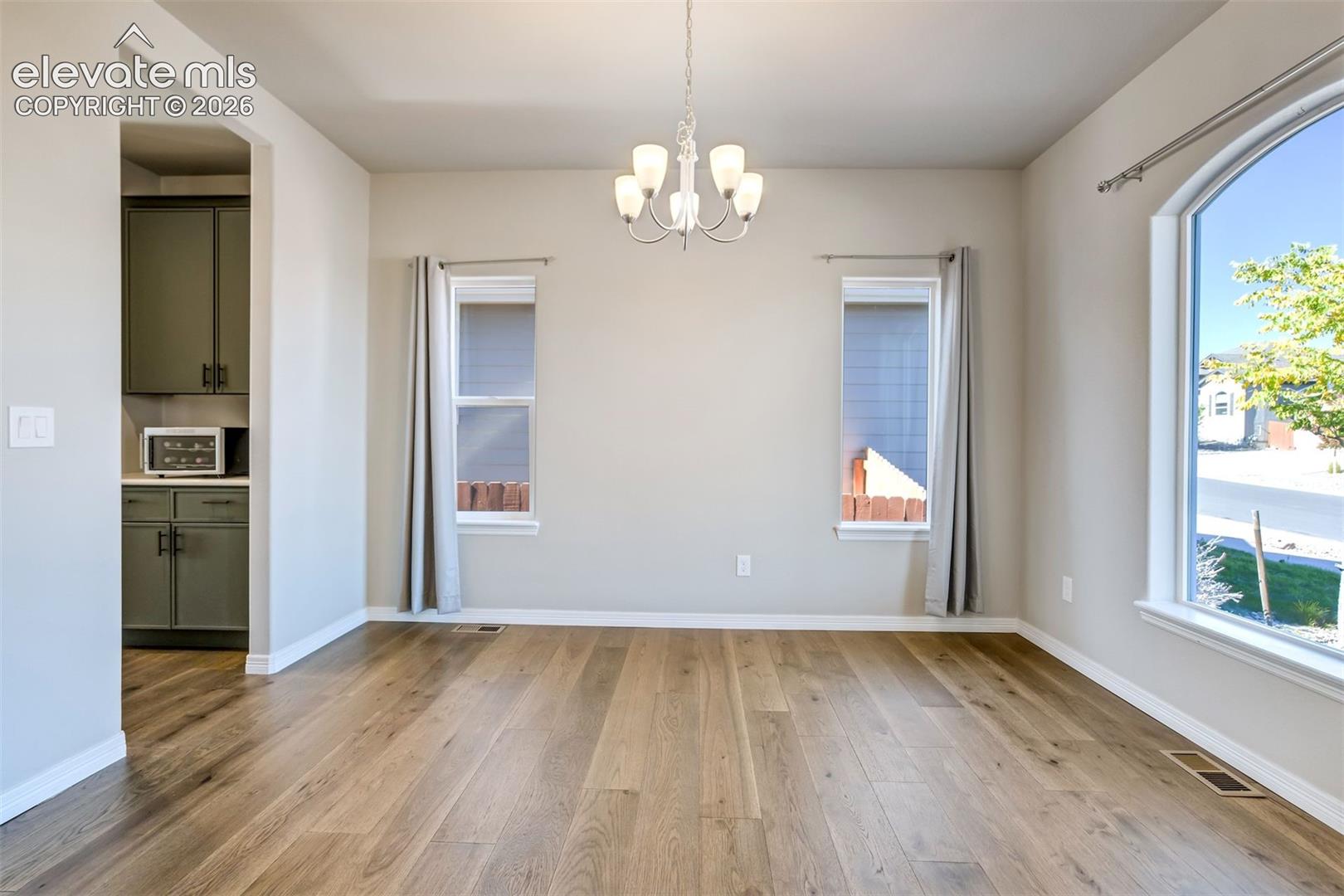 Wood-finish flooring throughout, complemented by a prominent arched window and two additional windows