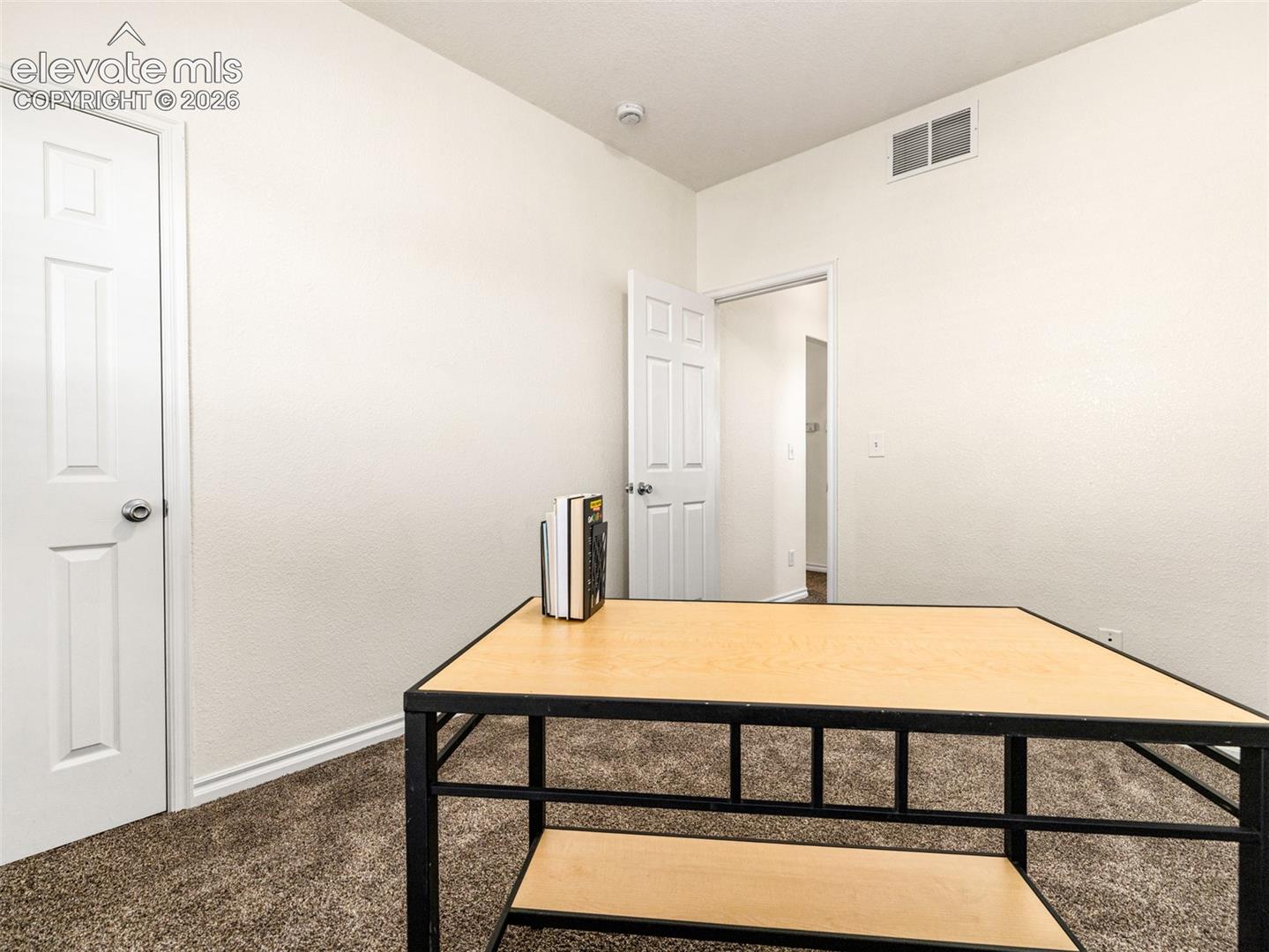 Carpeted room with white walls and a white paneled door