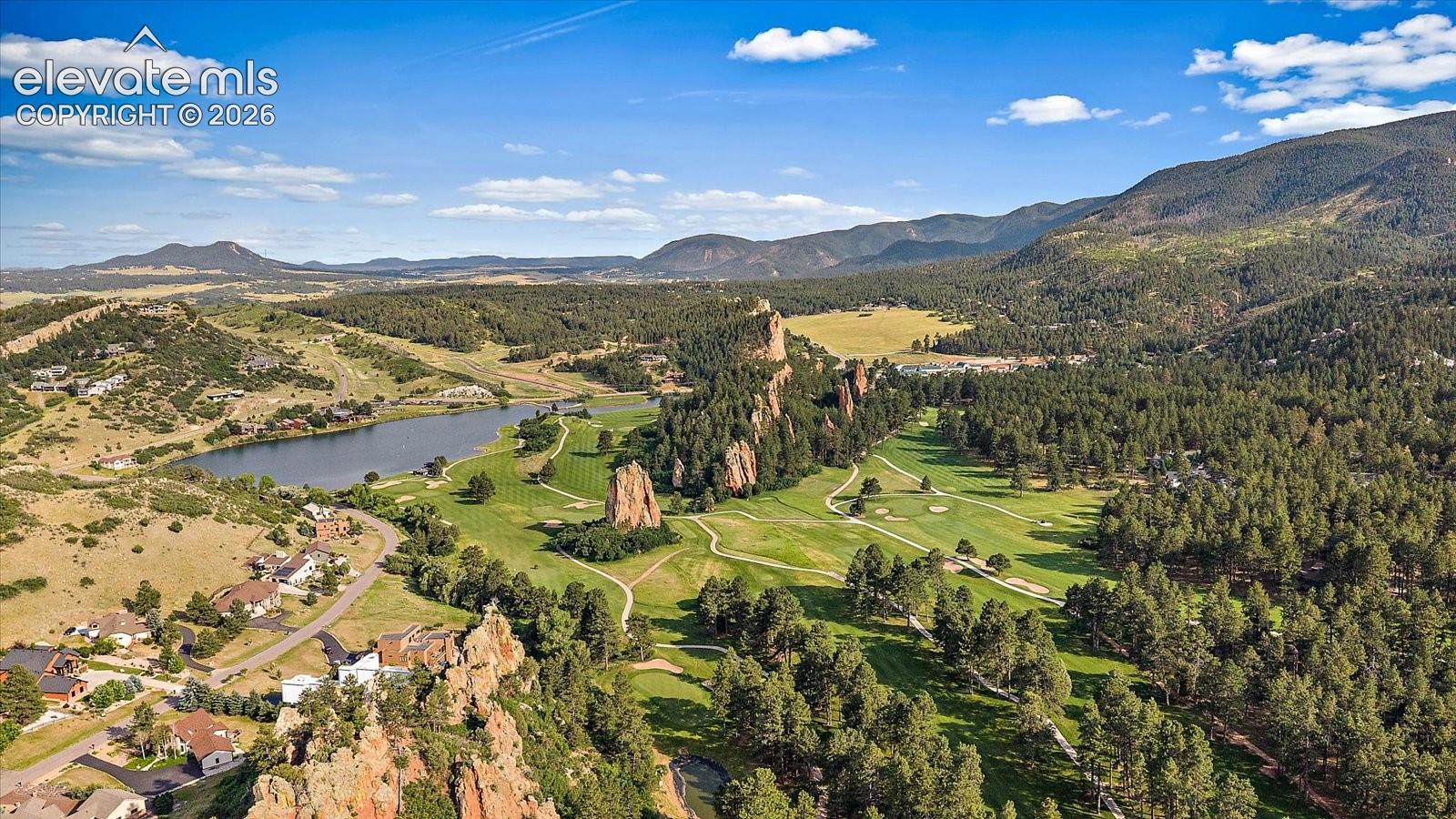 Aerial landscape featuring rock formations, a lake, forested areas, and open terrain