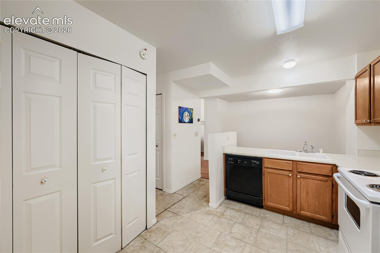 Bright kitchen featuring white six-panel cabinetry, wood-finish upper cabinetry, tile flooring, and stainless steel electric range
