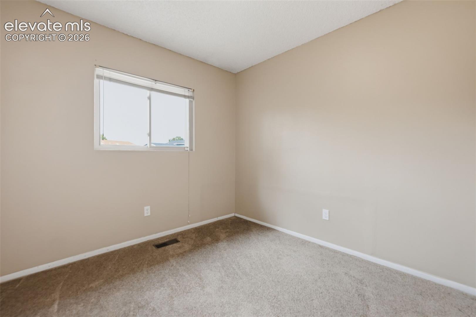 Neutral-toned walls with a window featuring horizontal blinds