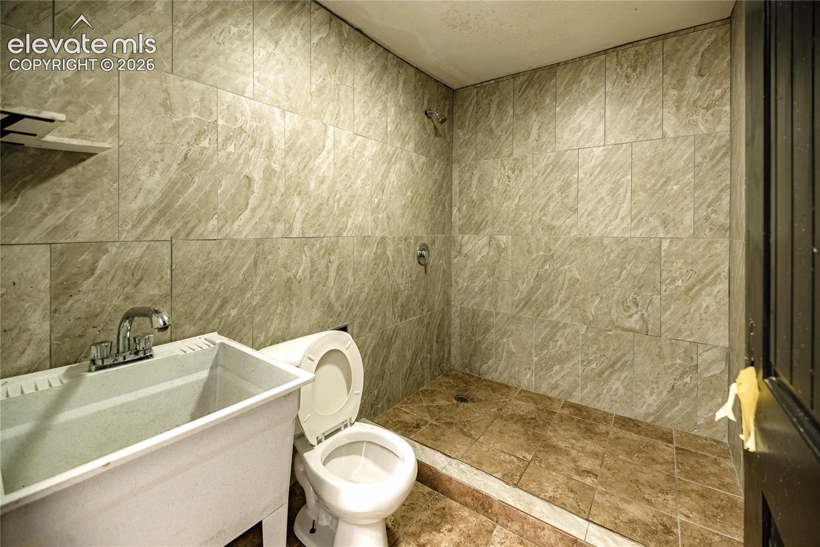 Tiled shower surround with a fixed showerhead, single-handle shower control, and coordinating tiled shower floor
