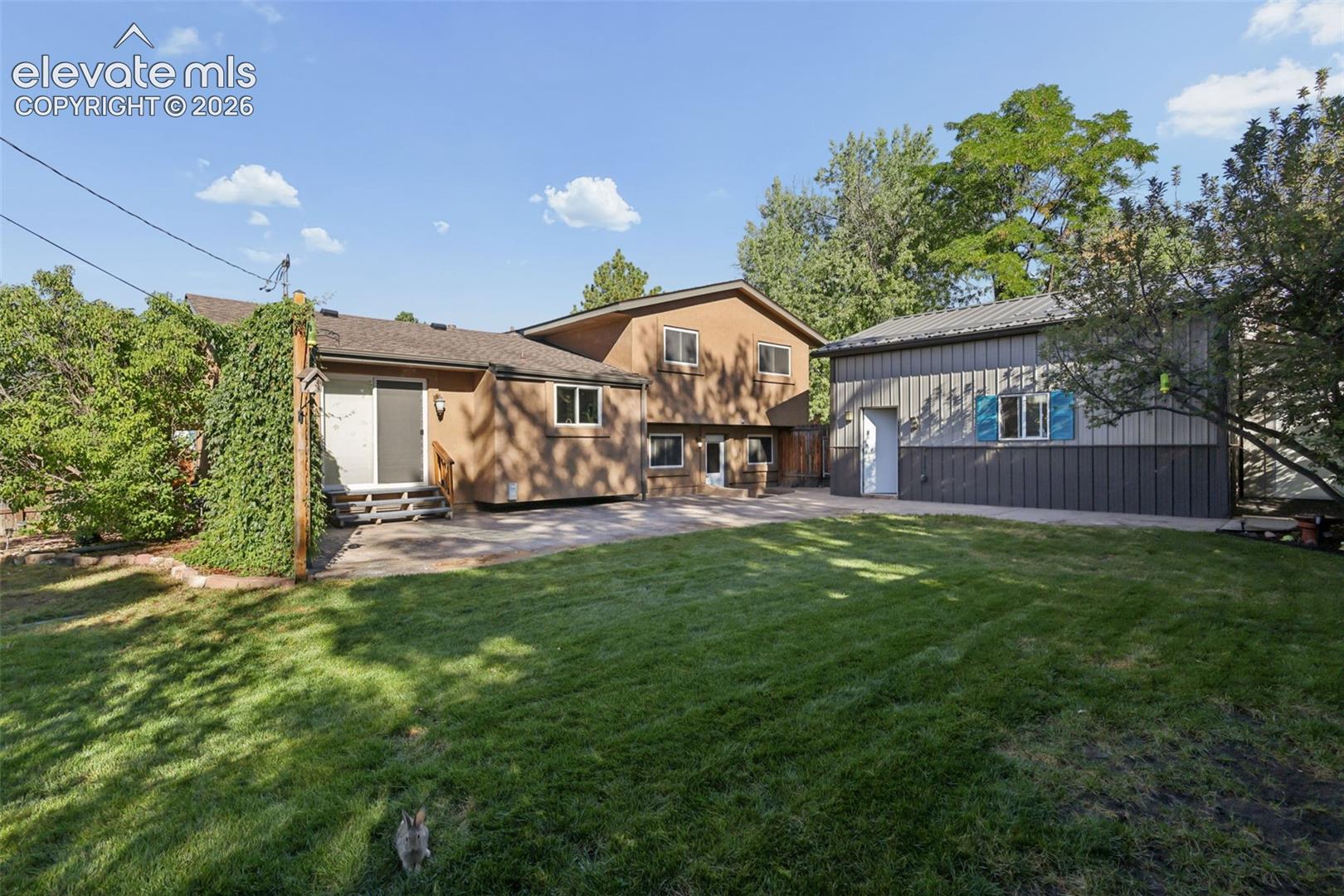 Rear side view of home with large expanded stamped concrete patio and beautiful landscaping!