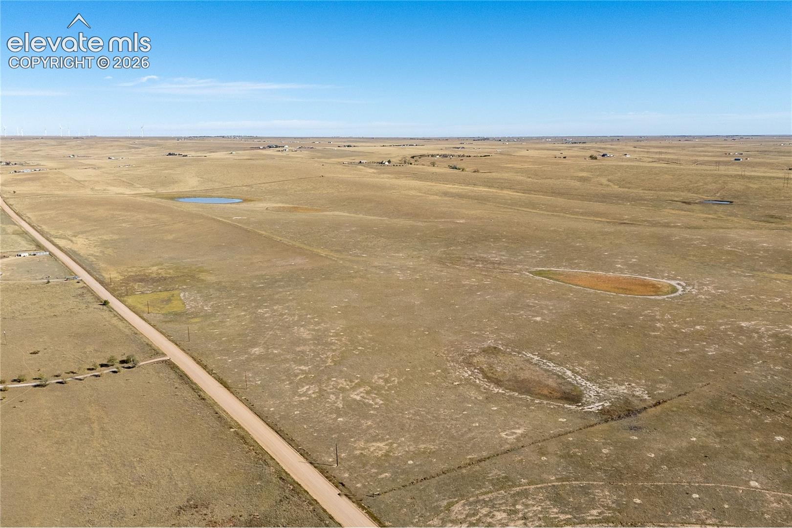 Expansive acreage featuring flat topography, native prairie grasslands, and multiple natural water basins with gravel road frontage