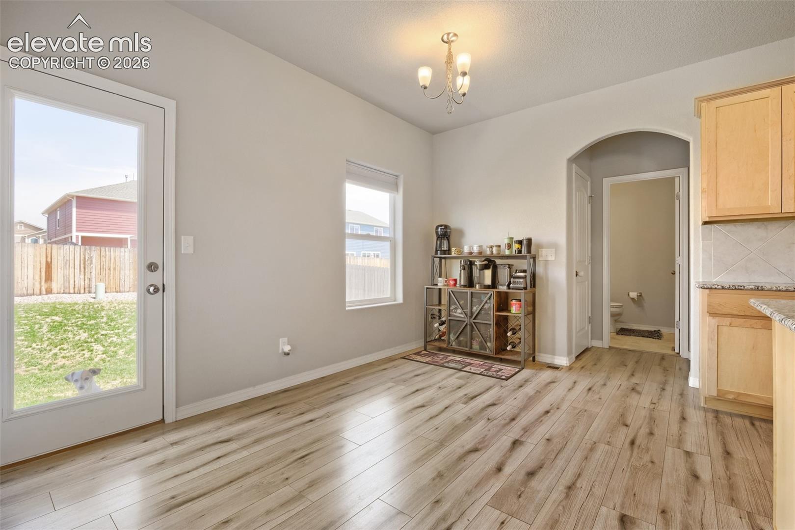 Light wood-finish flooring throughout, featuring a full-light patio door opening to the exterior