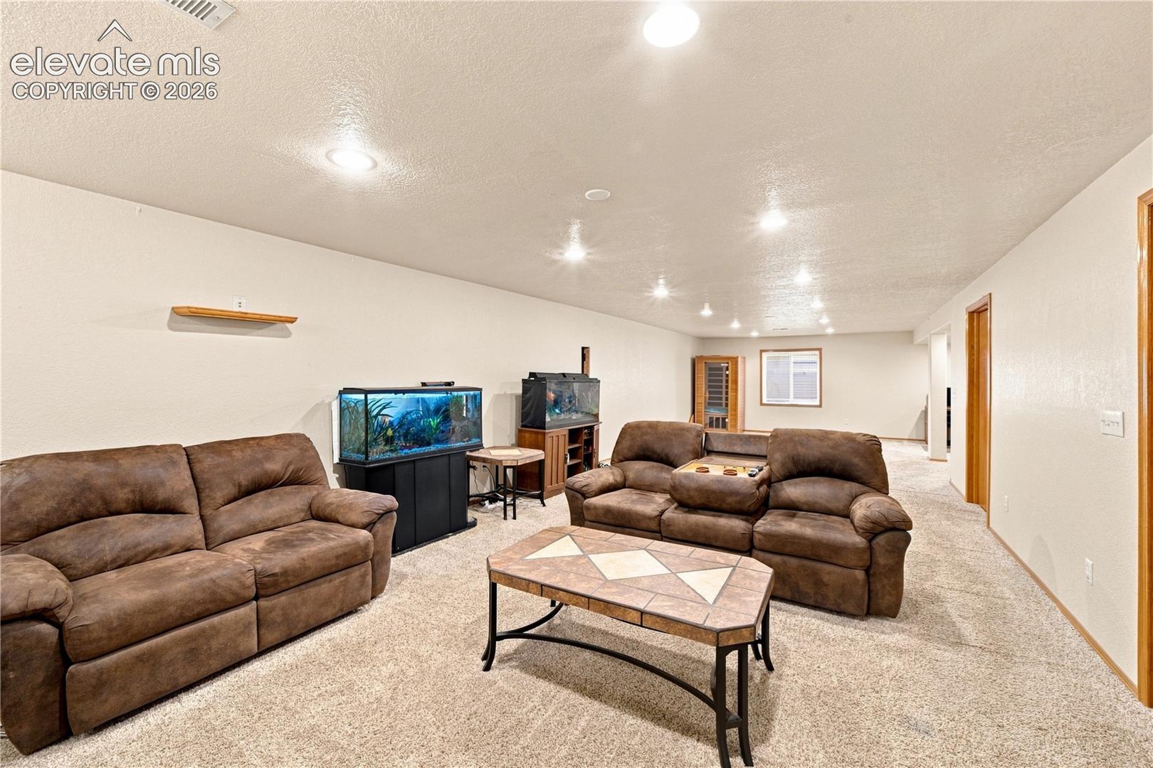 Spacious room featuring neutral carpeting, recessed lighting, wood-finish trim, and a built-in wall shelf