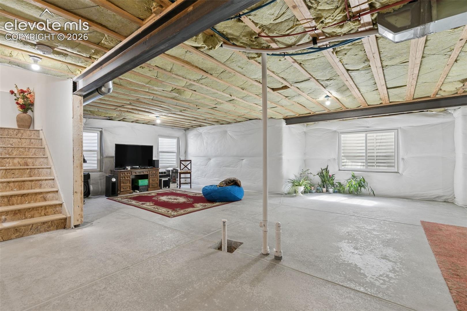 Expansive lower level with concrete flooring, exposed ceiling joists, and exposed structural steel beams