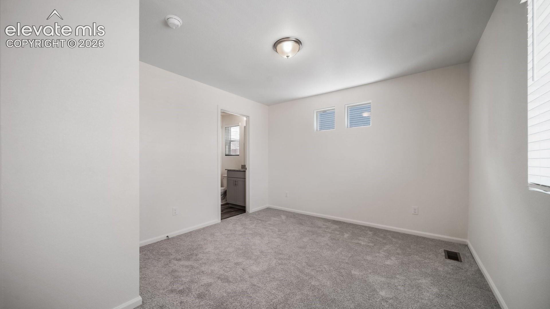 Neutral-toned interior featuring wall-to-wall carpeting, flush-mount ceiling lighting, and dual high-set windows
*photos of a model home*