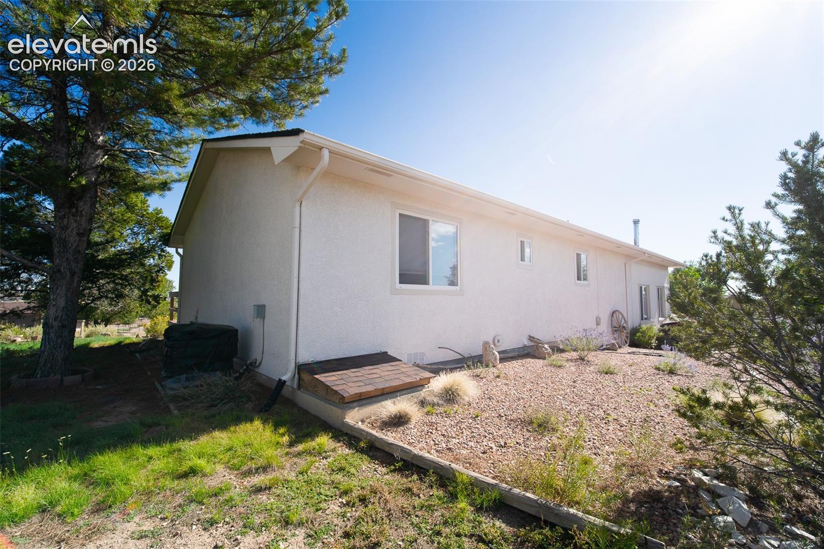 Stucco exterior featuring a low-pitch roofline, dual-pane windows, and a dedicated cellar egress entry