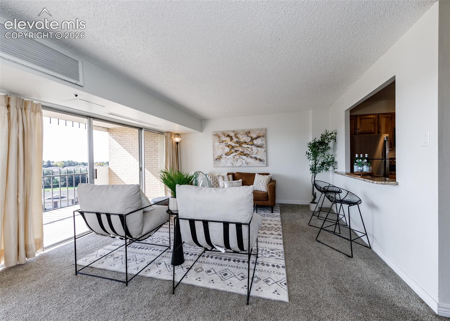 Living area featuring sliding glass doors, a stone-surfaced breakfast bar, and carpeted flooring