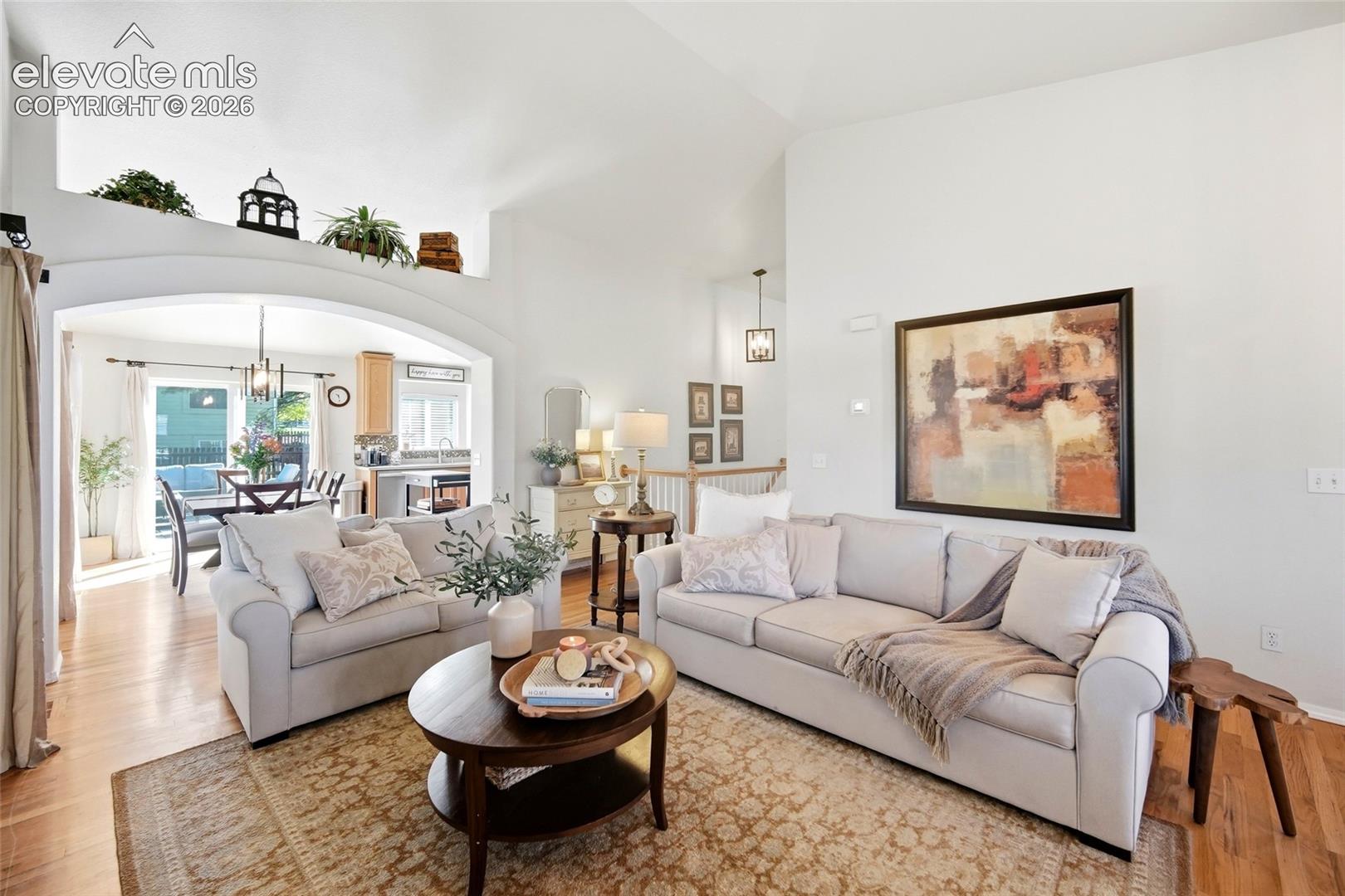 Vaulted ceiling, arched doorway, hardwood flooring, built-in shelving, and recessed lighting