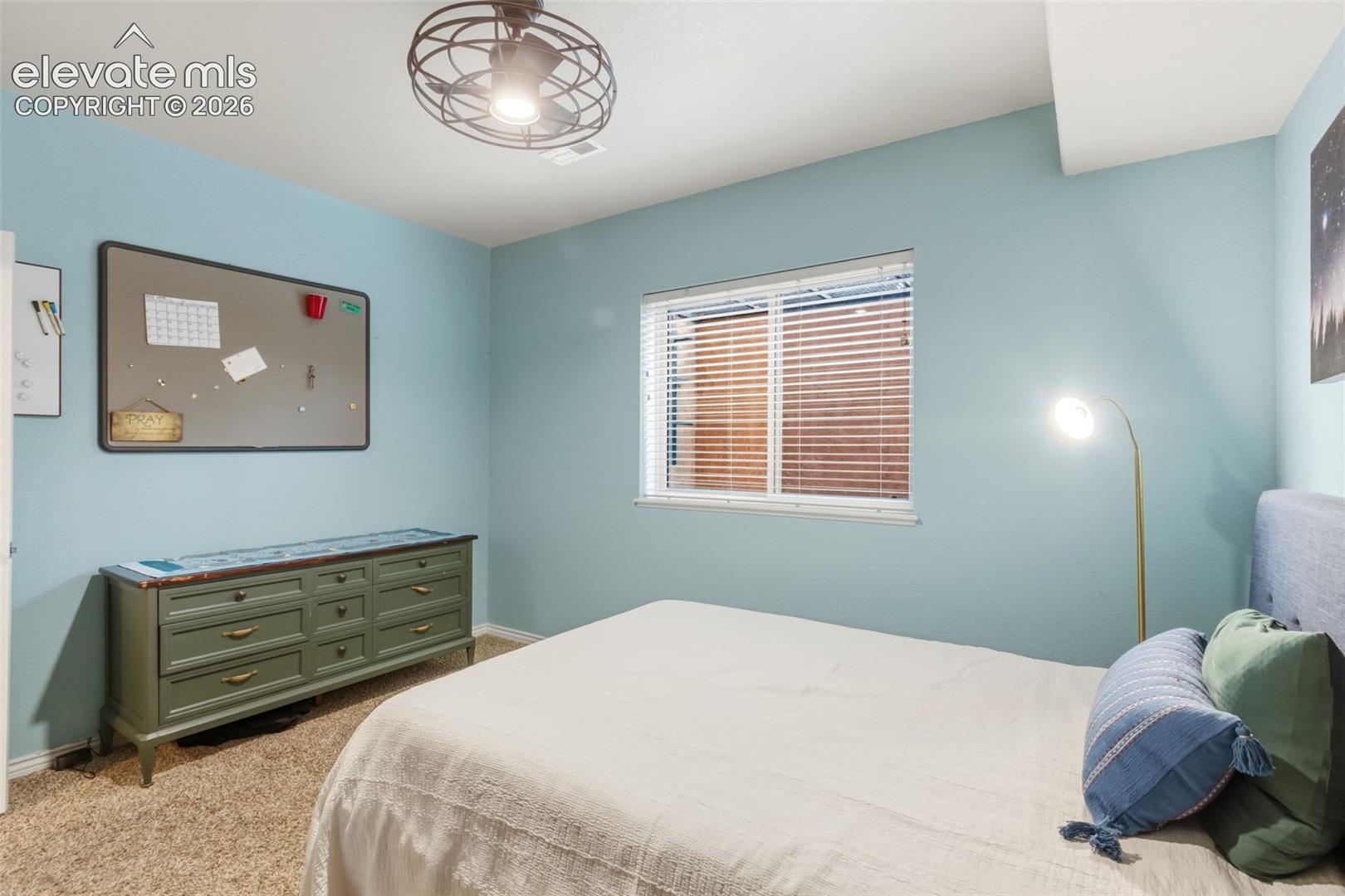 Carpeted room with light blue walls and a window featuring blinds